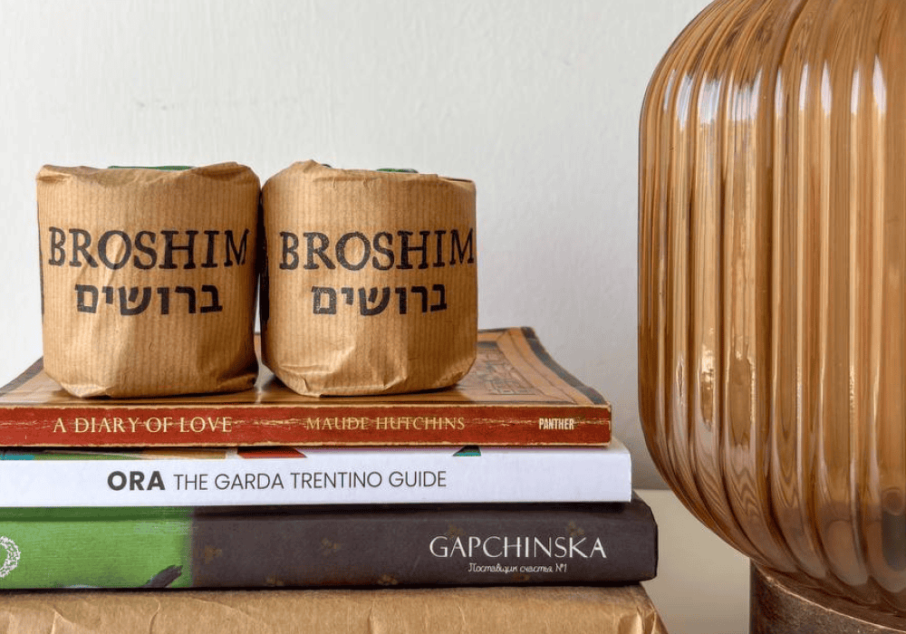 Бумажные мешки с надписью "Брошим" и книги на деревянной полке, интерьер в скандинавском стиле.